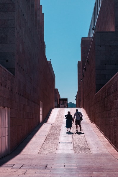 两个男人和一个女人走在建筑物之间的通路
